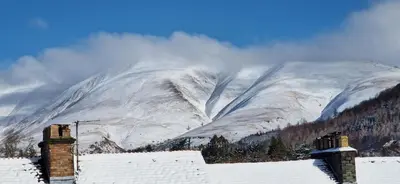 a snow covered mountain in front of a house at Glencoe Guest House in Keswick