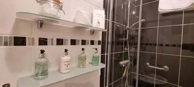 a bathroom with bottles on a shelf next to a shower at Glencoe Guest House in Keswick