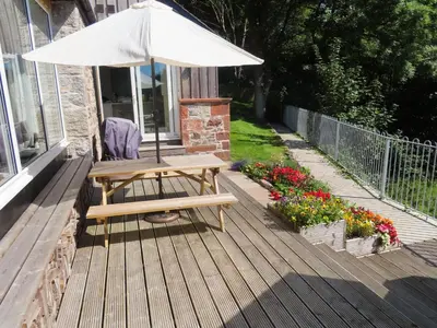 a picnic table with an umbrella on a deck at The Fish House in Kirkcudbright