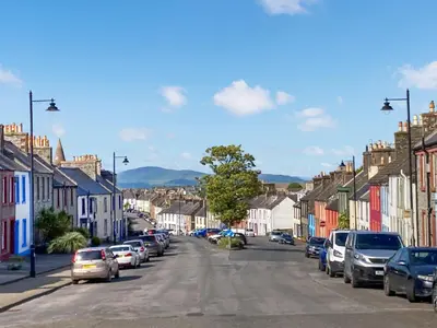 a street in a small town with parked cars at Brae Cottage in Whithorn
