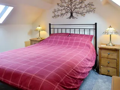 a bedroom with a purple bed and two night stands at Brae Cottage in Whithorn
