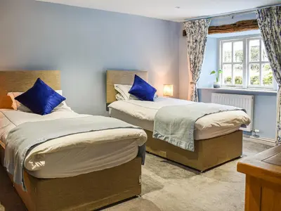 a bedroom with two beds with blue pillows at Forge Cottage in Keswick