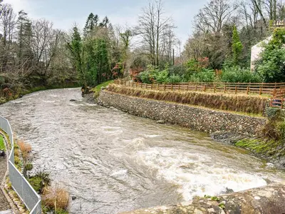 a stream of water with a fence next to it at Forge Cottage in Keswick
