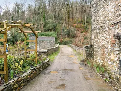 a dirt road next to a stone wall at Forge Cottage in Keswick