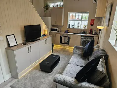 a living room with a couch and a kitchen at Carlisle Central, Cute Studio Appt, The Cupboard in Carlisle