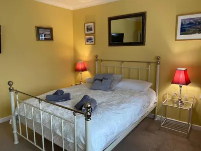 a bedroom with a bed with two lamps and a mirror at Strawberry Fields in Cockermouth