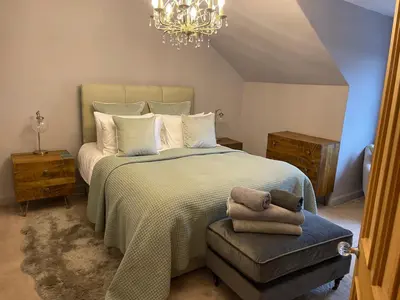 a bedroom with a large bed and a chandelier at River View in Dumfries