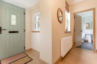 a hallway with a green door and a mirror at Balbeg Cottage in Straiton