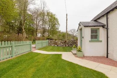 a yard with a fence and a house at Balbeg Cottage in Straiton