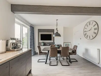 a kitchen and dining room with a table and a clock at Brooksyde,Kippford in Kippford