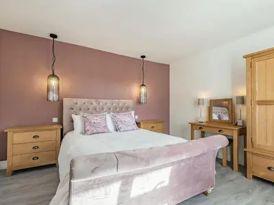a bedroom with a large bed with pink walls at Brooksyde,Kippford in Kippford