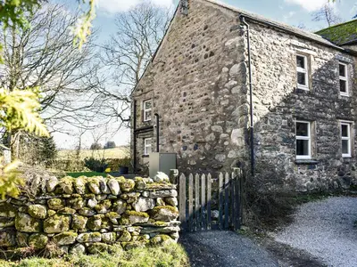 an old stone building with a fence next to it at Wallthwaite Cottage in Threlkeld