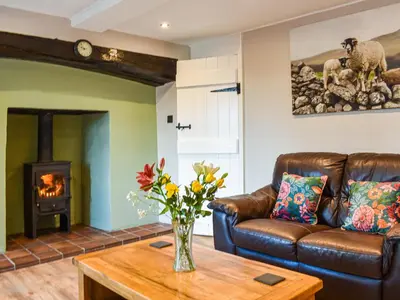 a living room with a leather couch and a fireplace at Wallthwaite Cottage in Threlkeld