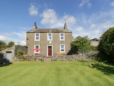 an old stone house with a lawn in front of it at Beckside Farm in Millom