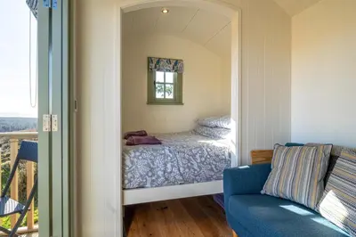a small bedroom with a bed and a window at Scalderskew Shepherds Hut in Gosforth