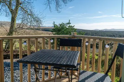 a table and two chairs on a deck with a view at Scalderskew Shepherds Hut in Gosforth