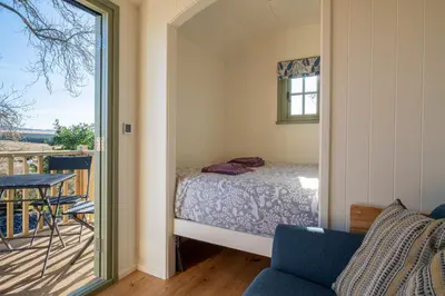 a bedroom with a bed and a balcony at Scalderskew Shepherds Hut in Gosforth