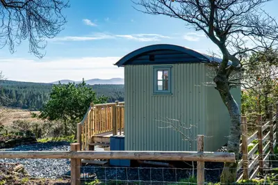 a green outhouse with a wooden fence at Scalderskew Shepherds Hut in Gosforth