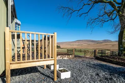 a wooden bench sitting outside of a house with a tree at Scalderskew Shepherds Hut in Gosforth