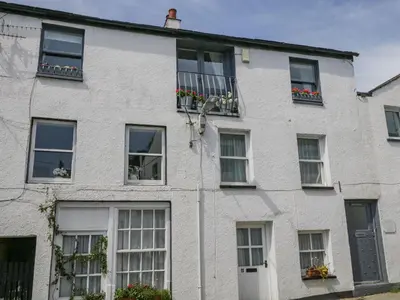 a white brick house with windows and flowers at The Old Mill in Keswick