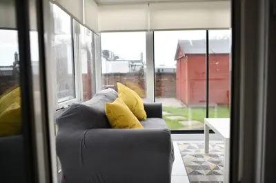 a gray couch with yellow pillows in a room with windows at The Prestwick Pad in Prestwick