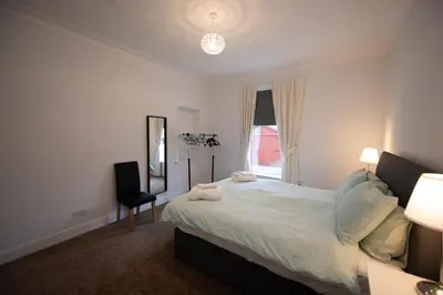 a bedroom with a bed and a chair and a window at The Prestwick Pad in Prestwick