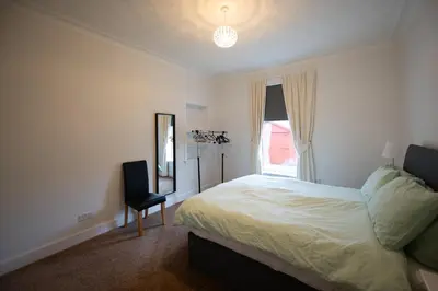 a bedroom with a bed and a mirror and a chair at The Prestwick Pad in Prestwick