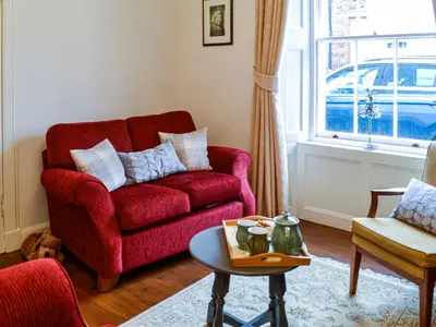 a living room with a red couch and a table at Sinclair's in Gatehouse of Fleet