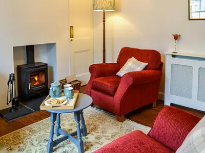 a living room with a red chair and a fireplace at Sinclair's in Gatehouse of Fleet