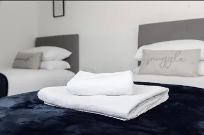 a stack of towels sitting on top of two beds at The Mila - Ayr Racecourse - Coorie Doon Stays in Ayr
