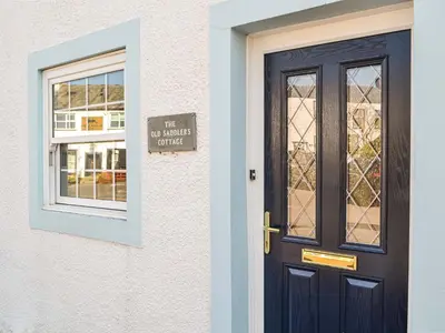 a door with a sign on it next to a window at Old Saddlers Cottage in Ireby