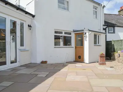 a white house with a door and a patio at Old Saddlers Cottage in Ireby