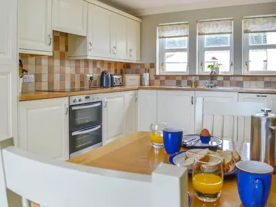 a kitchen with white cabinets and a wooden table with orange juice at Knockinaam House in Colfin