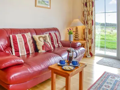 a red leather couch in a living room with a table at Knockinaam House in Colfin