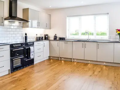 a kitchen with white cabinets and a wooden floor at Chestnuts in Burgh by Sands