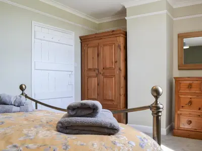 a bedroom with a bed with a wooden dresser at Fieldside Farmhouse in Tallentire