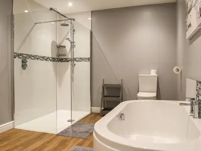 a bathroom with a shower and a white bath tub at Fieldside Farmhouse in Tallentire
