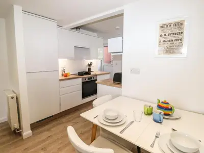 a white kitchen with a white table and chairs at Sparrow Cottage in Keswick