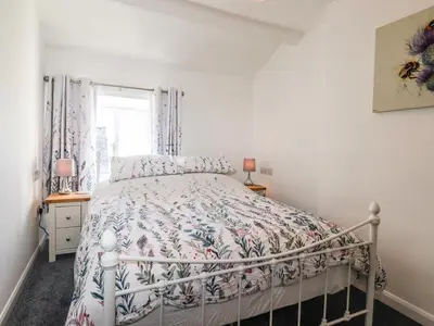 a bedroom with a bed with a floral bedspread at Sparrow Cottage in Keswick