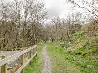 a dirt path next to a fence next to a river at Sparrow Cottage in Keswick