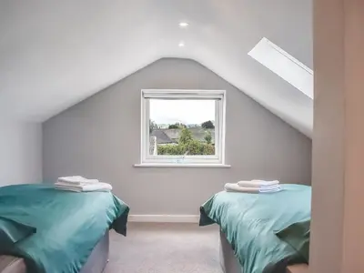 a attic room with two beds and a window at Rosedean in Ireby