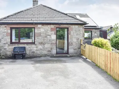 a stone house with a driveway in front of it at Rosedean in Ireby