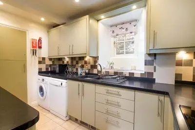 a kitchen with white cabinets and a sink and a dishwasher at Rhubarb Cottage in Chapel Stile