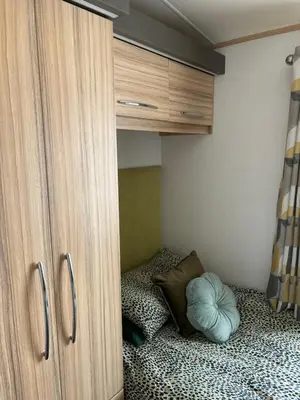 a bedroom with a bed and a wooden cabinet at Squirrel Lodge (Unit 7) in Carlisle