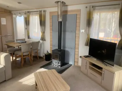 a living room with a stove and a dining table at Squirrel Lodge (Unit 7) in Carlisle
