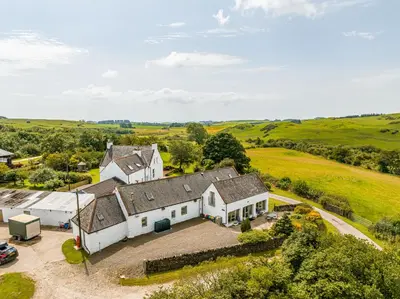an aerial view of a large white house in a field at The Steading at Castle Creavie Farm in Kirkcudbright