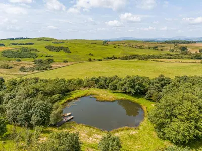 an aerial view of a lake in a field at The Steading at Castle Creavie Farm in Kirkcudbright