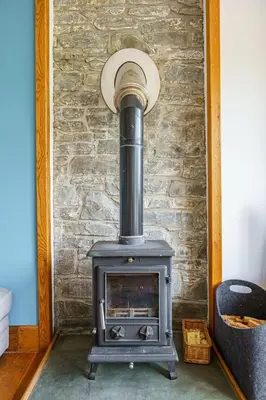 a stove in a room with a brick wall at The Steading at Castle Creavie Farm in Kirkcudbright