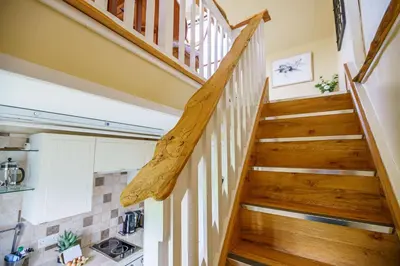 a staircase in a tiny house with wooden railings at The Cheeseloft - Spacious one bed with terrace in Kirkcudbright