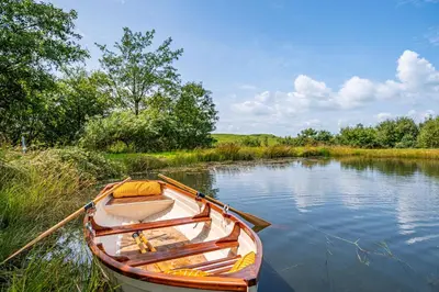 a wooden boat sitting on the side of a river at The Cheeseloft - Spacious one bed with terrace in Kirkcudbright